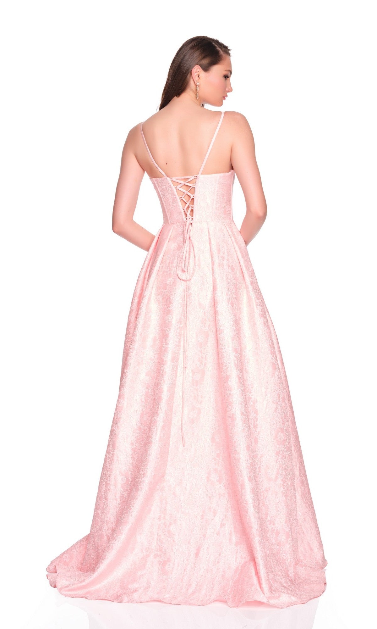 A woman stands with her back to the camera against a white background, wearing the Dave and Johnny 12885 long prom dress. The light pink gown features thin straps, a corset bodice, and a lace-up back.